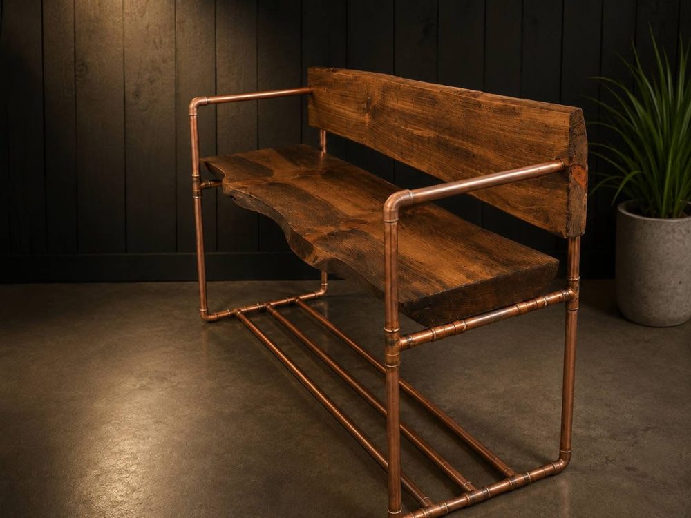 Bench with a copper pipe frame, a dark live-edge wood seat, a thick wood backrest and a copper rack underneath